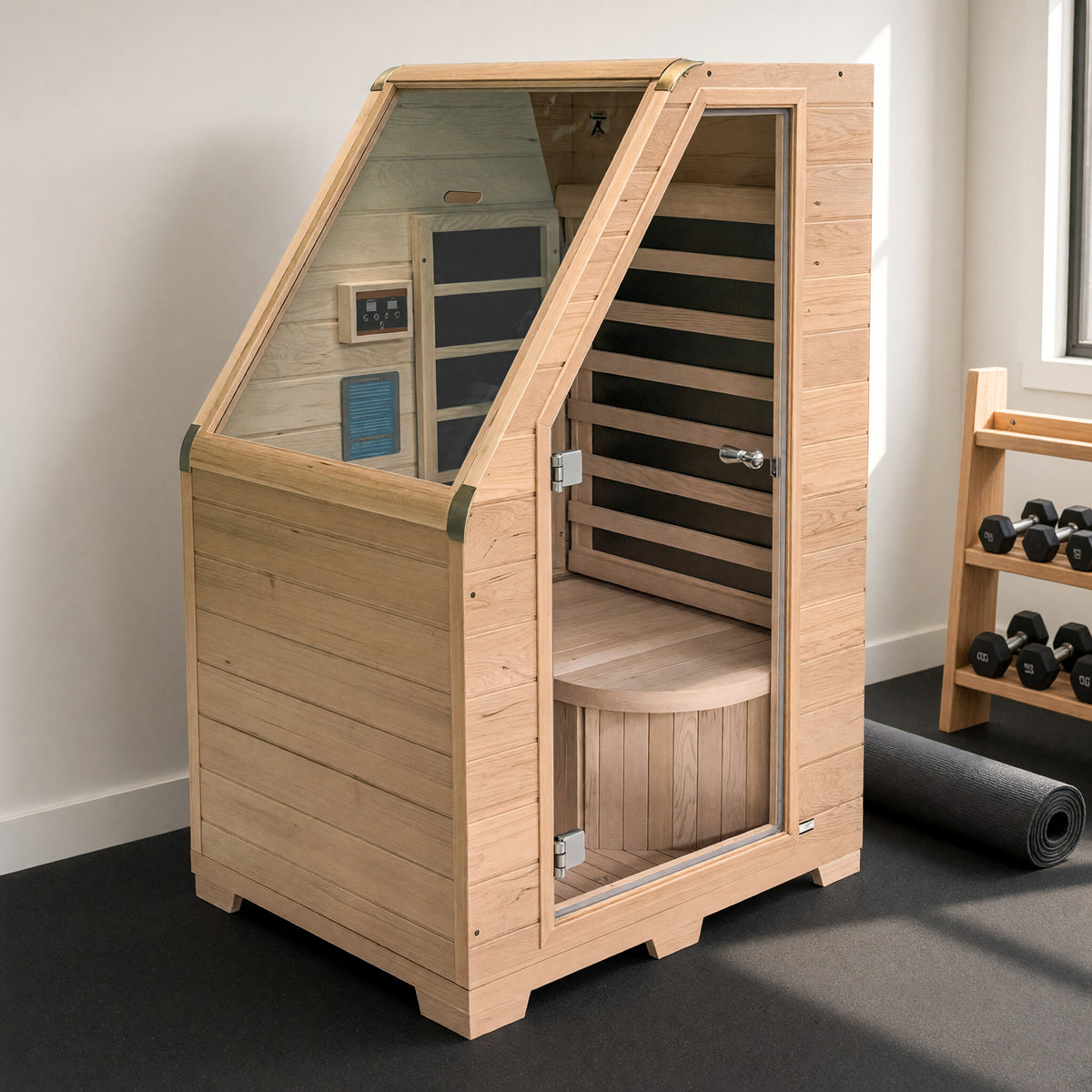 1-person Canadian hemlock infrared sauna set up in a home gym, glass door open showing the bench and carbon heater panels